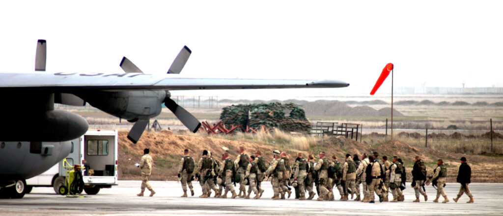 US Army troops walk across the flightline at Karshi-Karnabad Air Base on their way to a C-130 Hercules to fly to a forward-deployed location supporting Operation Enduring Freedom in 2005. [USAF/TSgt Scott T. Sturkol]
