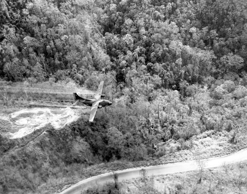 A ‘Ranch Hand’ UC-123 deploying a defoliant (either Agent White or more likely Agent Orange) to clear a roadside in central South Vietnam in 1966. [USAF]